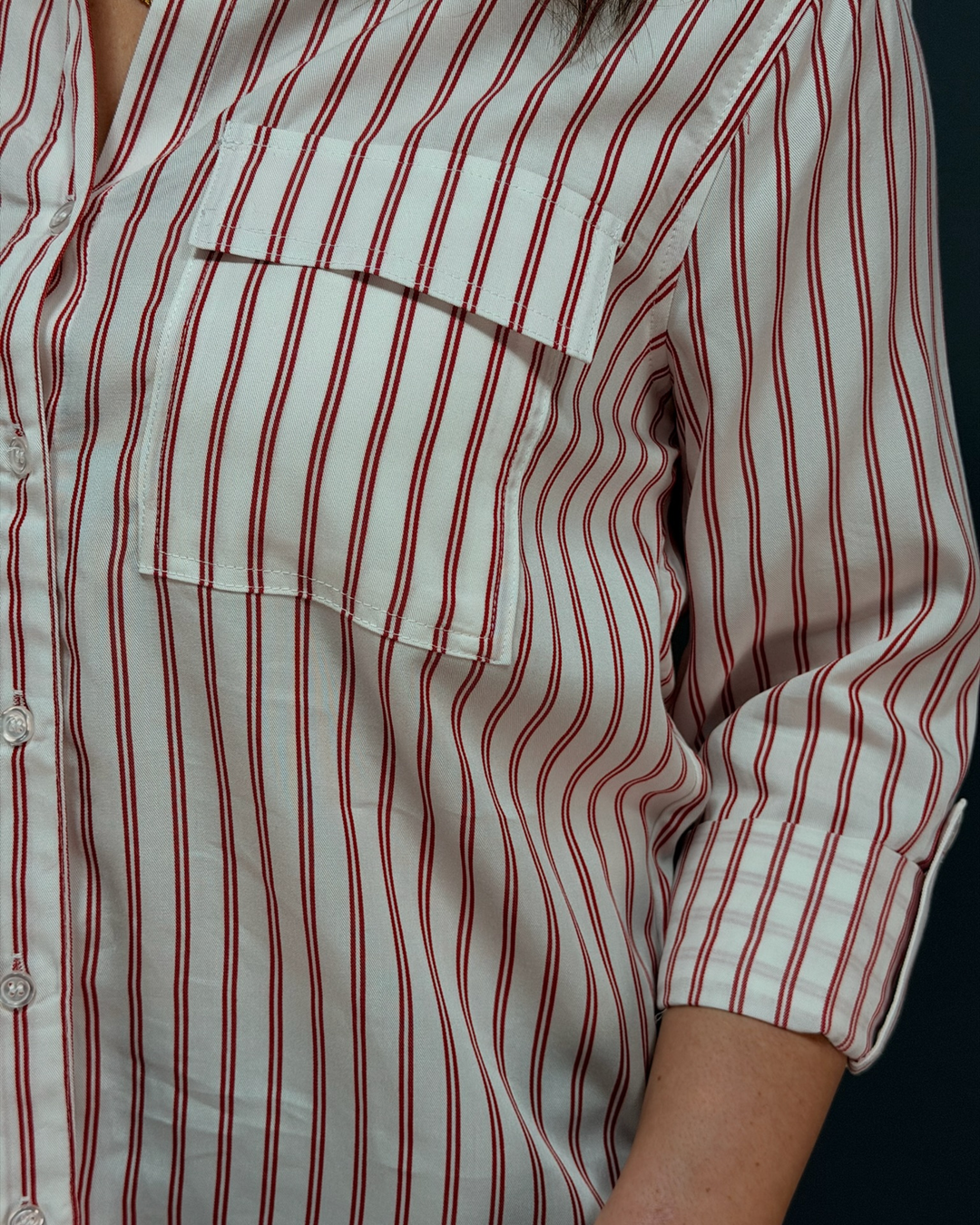 woman wearing a red and white striped button down top in front of a gray background