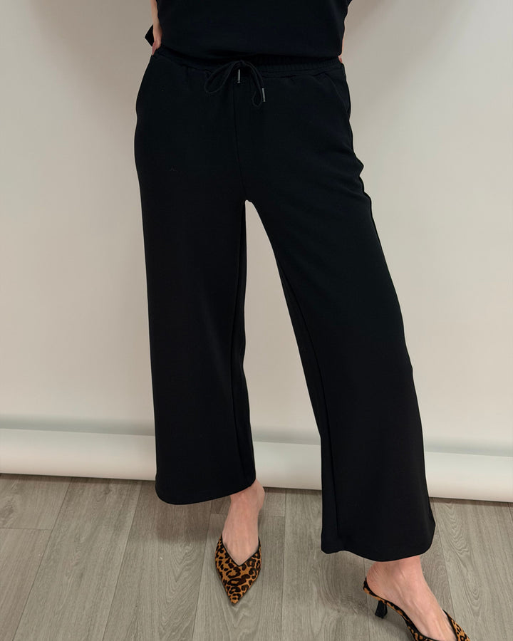 Person wearing black wide-leg pants with a plain background