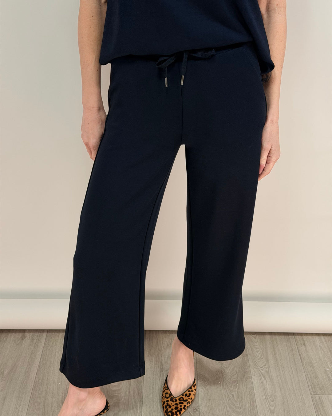 Person wearing navy wide-leg pants and a dark top against a neutral background