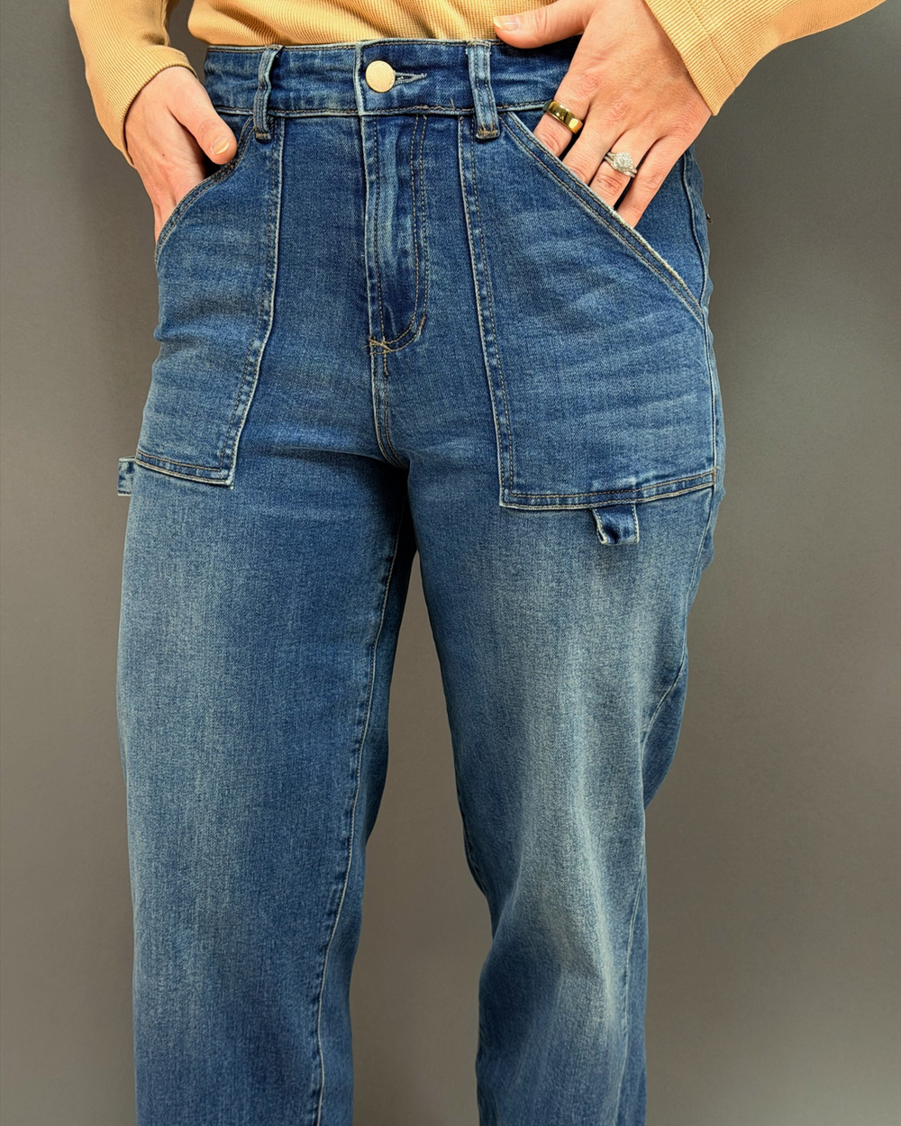 woman wearing wide leg painter style jeans in front of a gray background