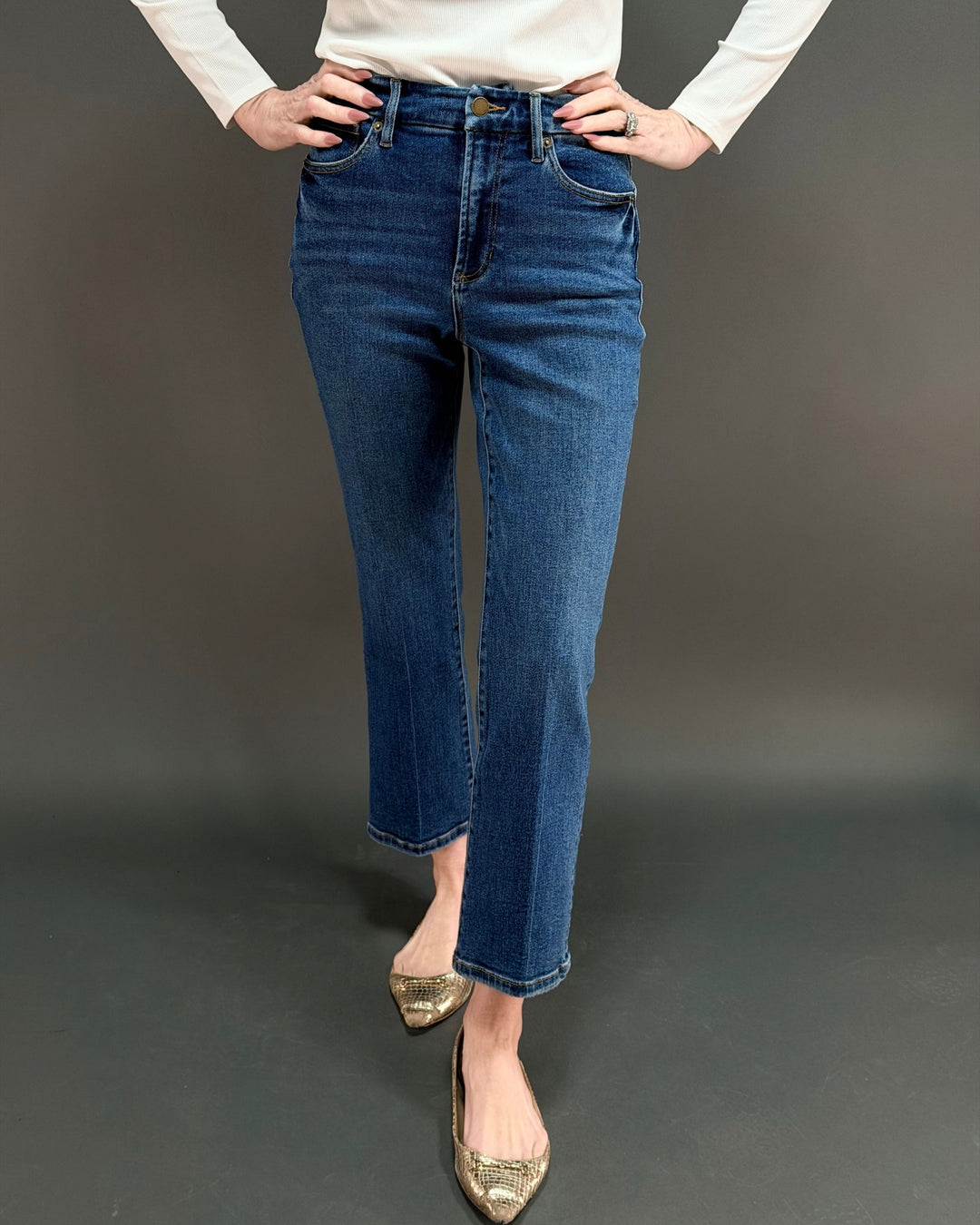 woman wearing cropped flared jeans in front of gray background