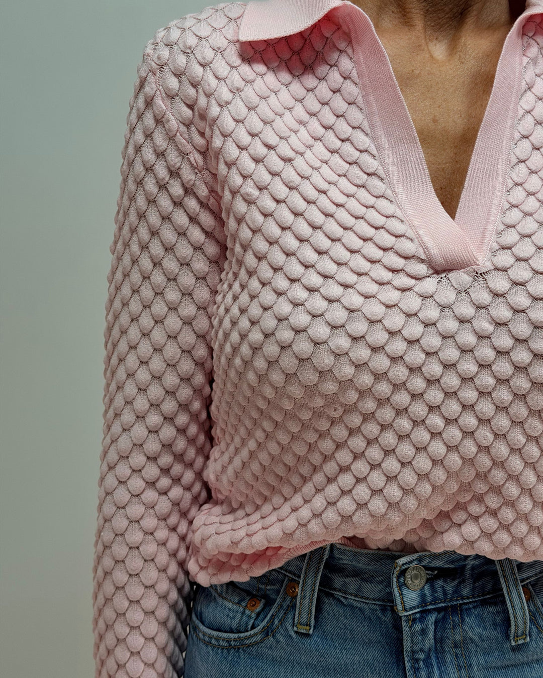 Pink textured sweater worn by a person against a plain background