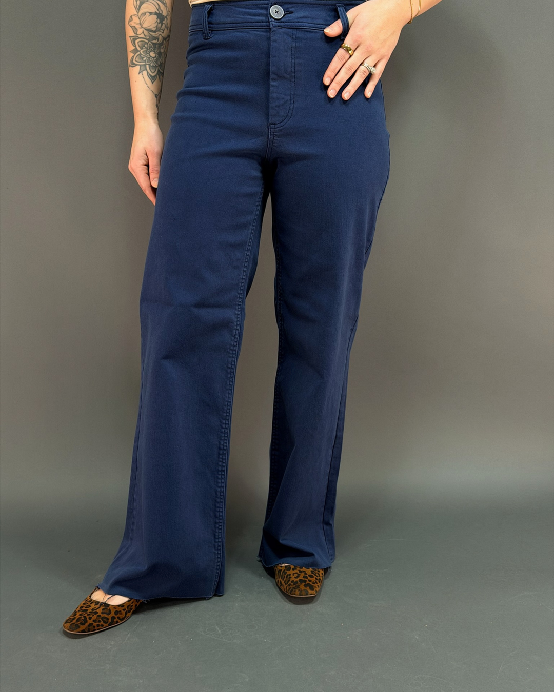 woman wearing navy wide leg pant in front of a gray background