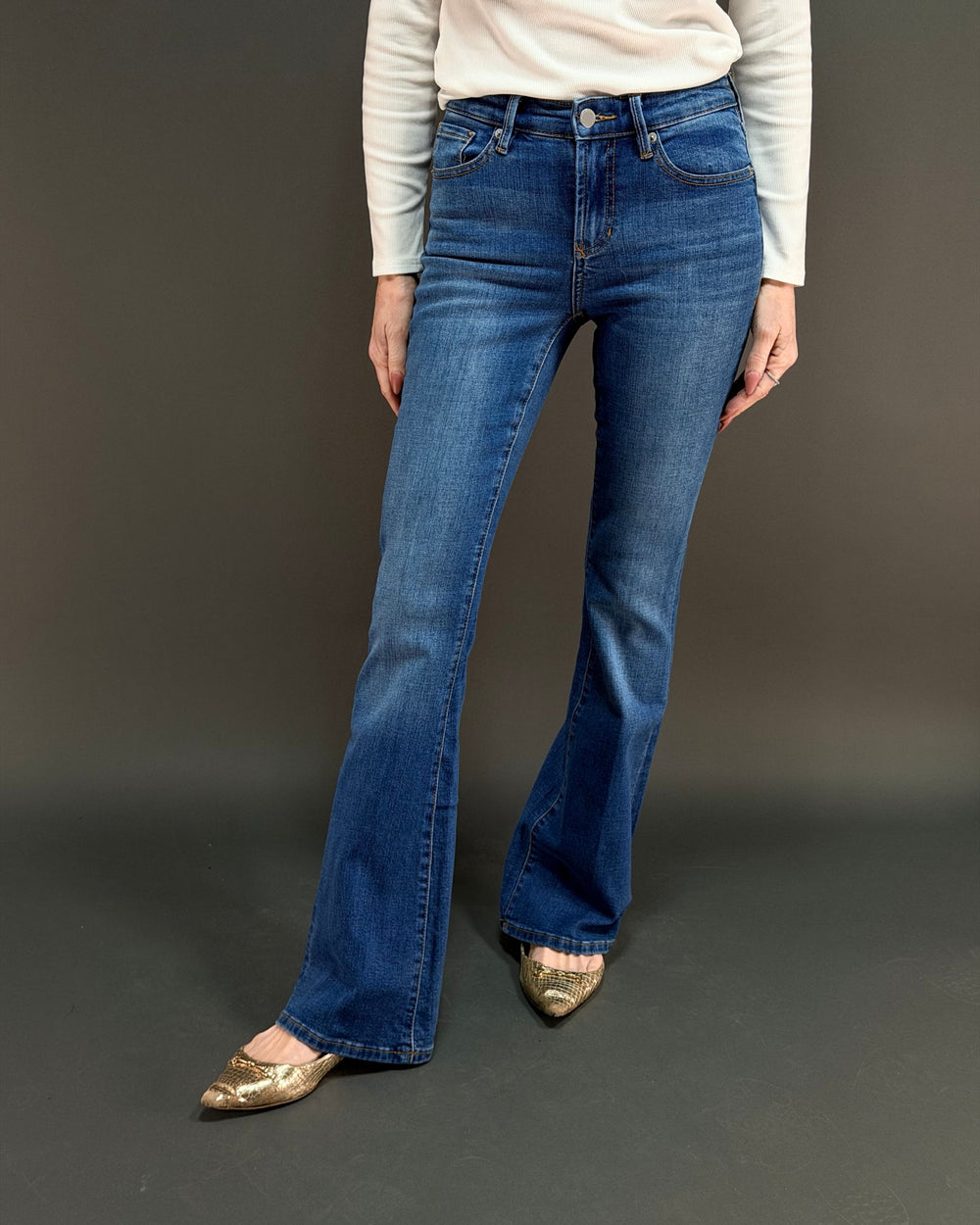 woman wearing flared jeans in front of gray background