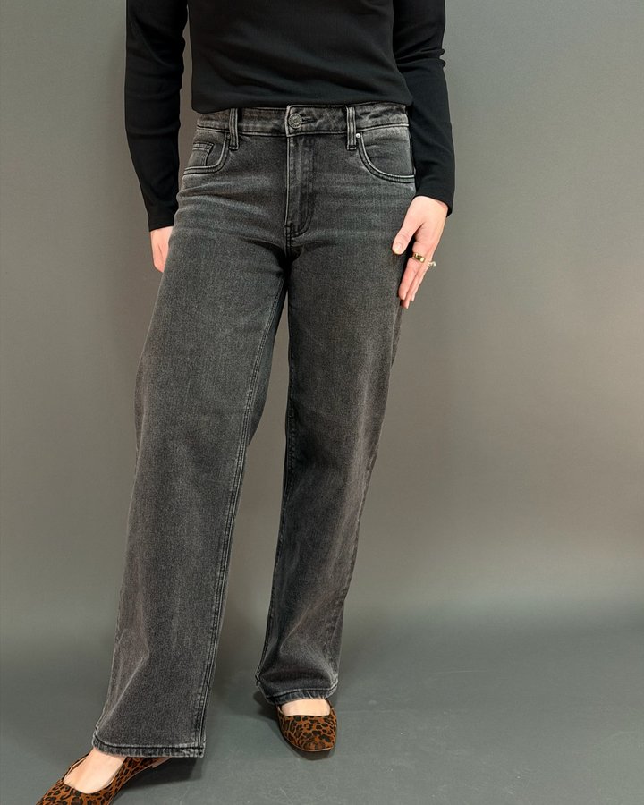 woman wearing charcoal colored jeans in front of a gray background