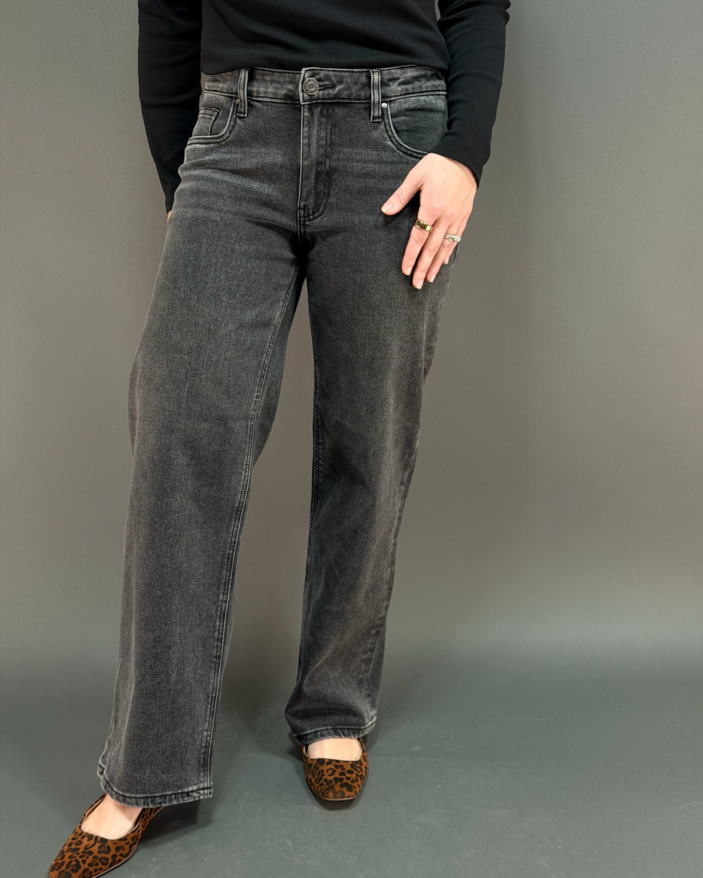 woman wearing charcoal colored jeans in front of a gray background