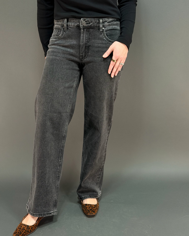 woman wearing charcoal colored jeans in front of a gray background