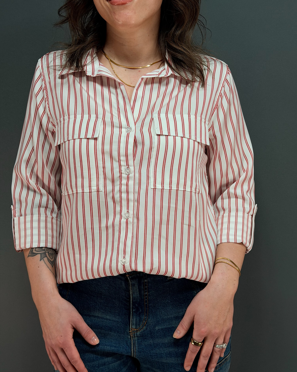 Woman wearing a red and white striped button with jeans in front of gray background